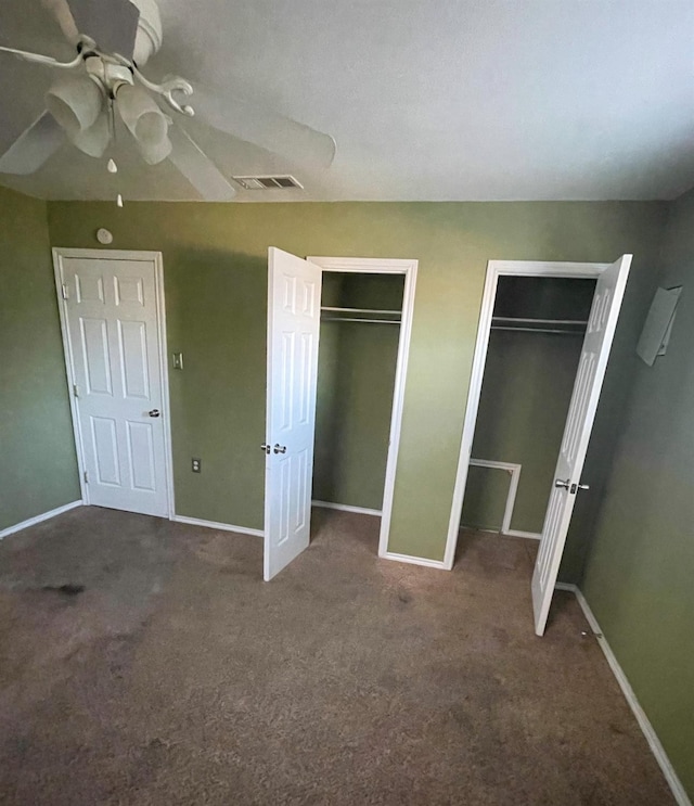 unfurnished bedroom with carpet flooring, a ceiling fan, visible vents, baseboards, and two closets