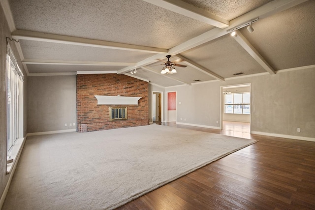 unfurnished living room with a fireplace, lofted ceiling with beams, hardwood / wood-style flooring, ceiling fan, and a textured ceiling