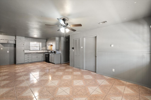 kitchen with black range oven, light tile patterned floors, gray cabinetry, and ceiling fan