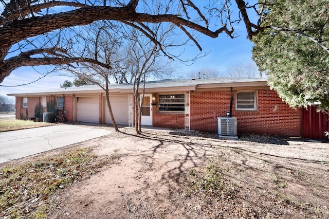 single story home with cooling unit and a garage