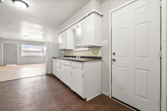 kitchen featuring white cabinetry, sink, dark hardwood / wood-style flooring, decorative backsplash, and white fridge