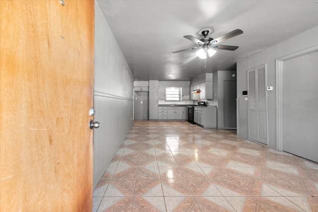 kitchen with light tile patterned flooring, gray cabinetry, black range, and ceiling fan