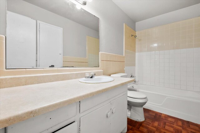 full bathroom featuring tile walls, tiled shower / bath combo, vanity, parquet flooring, and toilet