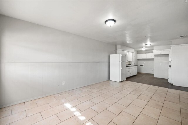 kitchen featuring white refrigerator, light tile patterned floors, and white cabinets