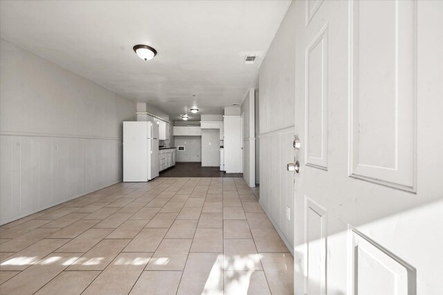 kitchen with white fridge, light tile patterned floors, and white cabinets