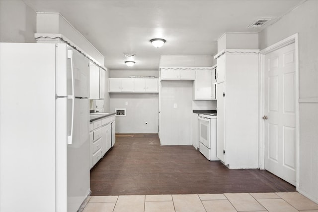 kitchen with white appliances, white cabinets, and light tile patterned flooring