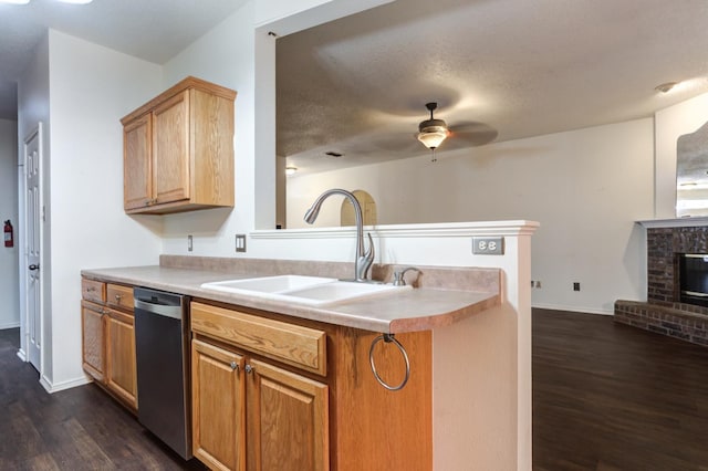 kitchen featuring a fireplace, dishwasher, sink, dark hardwood / wood-style flooring, and kitchen peninsula