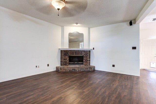 unfurnished living room featuring dark hardwood / wood-style flooring, a brick fireplace, a textured ceiling, and ceiling fan