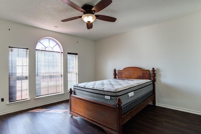 bedroom with ceiling fan, dark wood-type flooring, and a textured ceiling