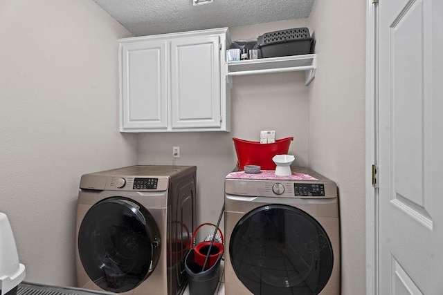 clothes washing area featuring washing machine and dryer, cabinets, and a textured ceiling