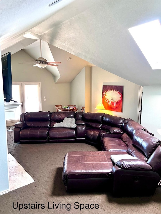 living room featuring ceiling fan, carpet flooring, and lofted ceiling with skylight