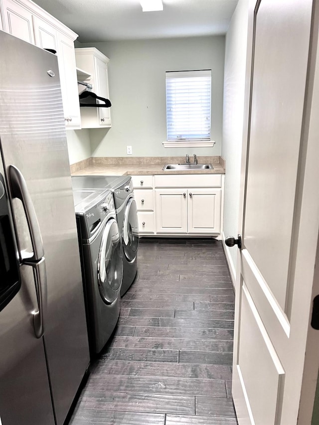 washroom featuring cabinets, sink, dark wood-type flooring, and washing machine and clothes dryer