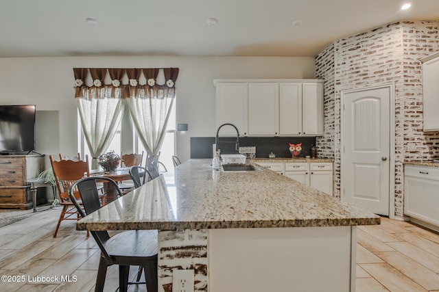 14320 Ave U, Lubbock, TX 79423 - kitchen with a kitchen bar, light stone counters, and white cabinetry