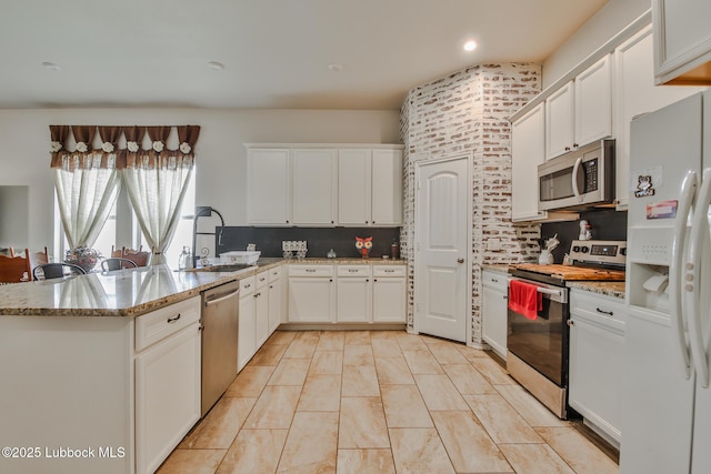 14320 Ave U, Lubbock, TX 79423 - kitchen featuring appliances with stainless steel finishes, tasteful backsplash, white cabinets, light stone counters, and recessed lighting