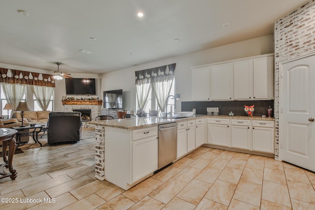 14320 Ave U, Lubbock, TX 79423 - kitchen with stainless steel dishwasher, ceiling fan, a peninsula, a fireplace, and white cabinets