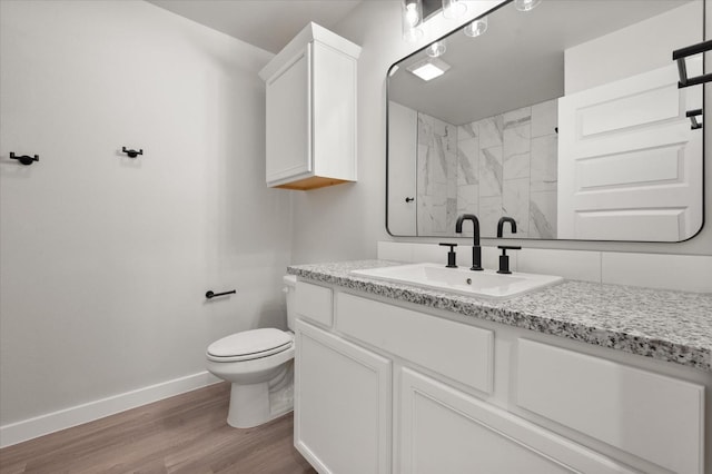 bathroom featuring hardwood / wood-style flooring, vanity, tiled shower, and toilet