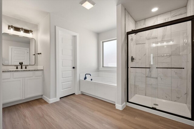 bathroom featuring hardwood / wood-style flooring, plus walk in shower, and vanity