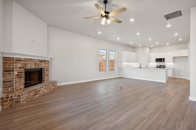 unfurnished living room with hardwood / wood-style flooring, a fireplace, and ceiling fan