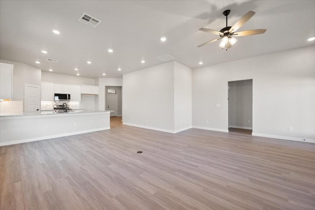 unfurnished living room featuring ceiling fan and light wood-type flooring