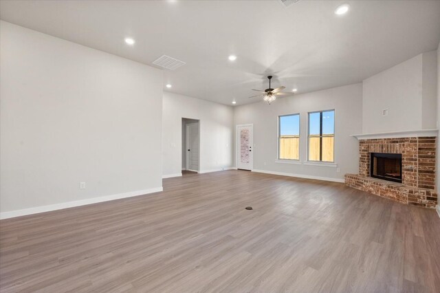 unfurnished living room featuring ceiling fan, a fireplace, and light hardwood / wood-style flooring