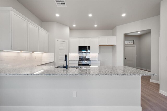 kitchen with sink, tasteful backsplash, stainless steel appliances, light stone countertops, and white cabinets