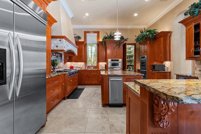 kitchen with pendant lighting, stainless steel appliances, a center island, light stone countertops, and decorative backsplash