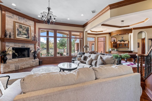 living room with crown molding, a fireplace, a chandelier, and hardwood / wood-style floors