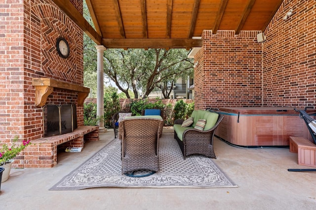 view of patio with an outdoor brick fireplace and a hot tub