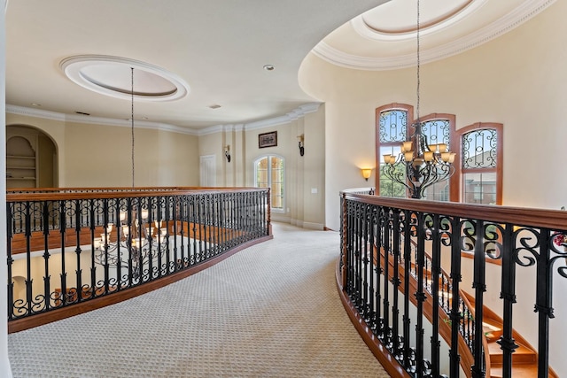 hallway featuring an inviting chandelier, light colored carpet, ornamental molding, and a tray ceiling