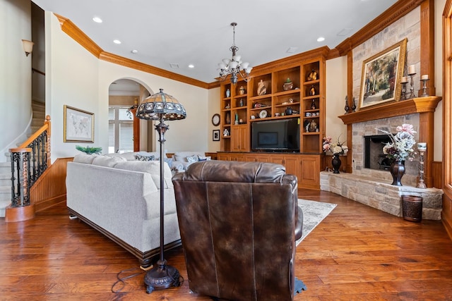 living room with a notable chandelier, a fireplace, ornamental molding, and wood-type flooring