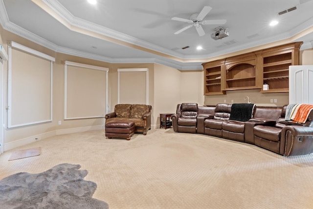 home theater room with a tray ceiling, ornamental molding, and carpet flooring