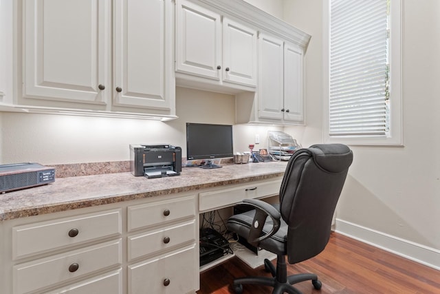 office with wood-type flooring and built in desk