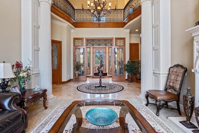 entrance foyer featuring decorative columns, a high ceiling, and a chandelier