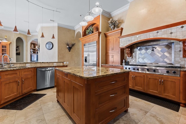 kitchen featuring sink, crown molding, appliances with stainless steel finishes, light stone counters, and a kitchen island