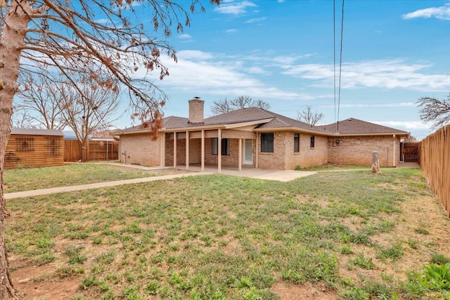 back of property featuring a chimney, a patio, a fenced backyard, and a yard