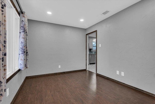 empty room with visible vents, baseboards, wood finished floors, and a healthy amount of sunlight