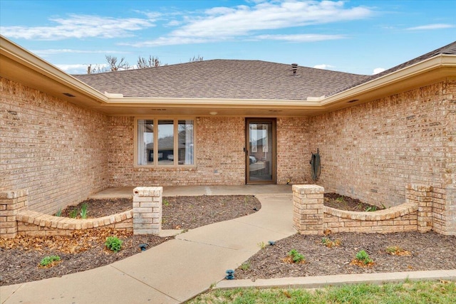 property entrance with roof with shingles and brick siding