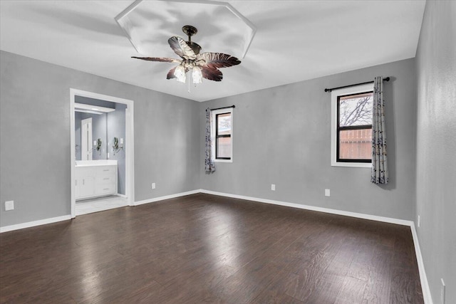 empty room with wood finished floors, a ceiling fan, and baseboards