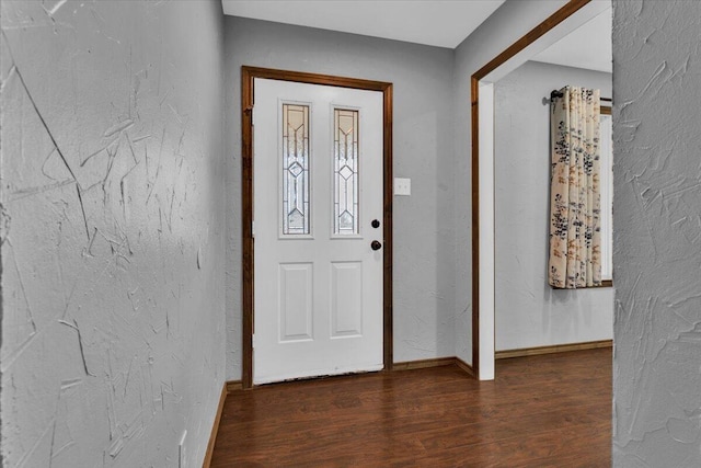 foyer featuring wood finished floors, a textured wall, and baseboards
