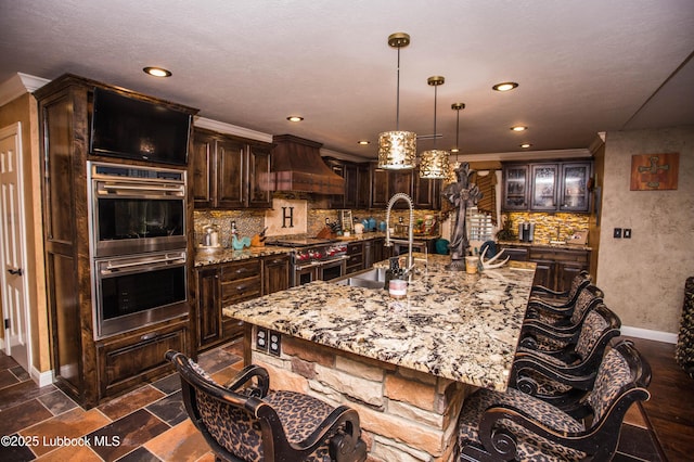 610 N 20th St, Lamesa, TX 79331 - kitchen featuring stainless steel appliances, premium range hood, a large island with sink, tasteful backsplash, and crown molding