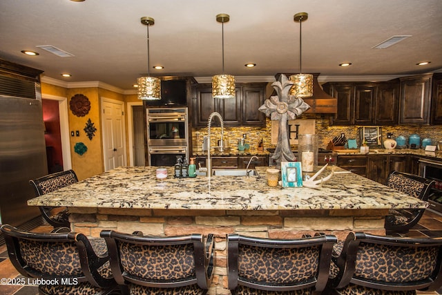 610 N 20th St, Lamesa, TX 79331 - kitchen with appliances with stainless steel finishes, crown molding, light stone counters, custom range hood, and dark brown cabinets