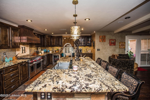 610 N 20th St, Lamesa, TX 79331 - kitchen featuring range with two ovens, custom range hood, light stone countertops, tasteful backsplash, and dark brown cabinets