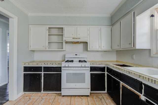 kitchen featuring ornamental molding, white gas range, a textured ceiling, and white cabinets