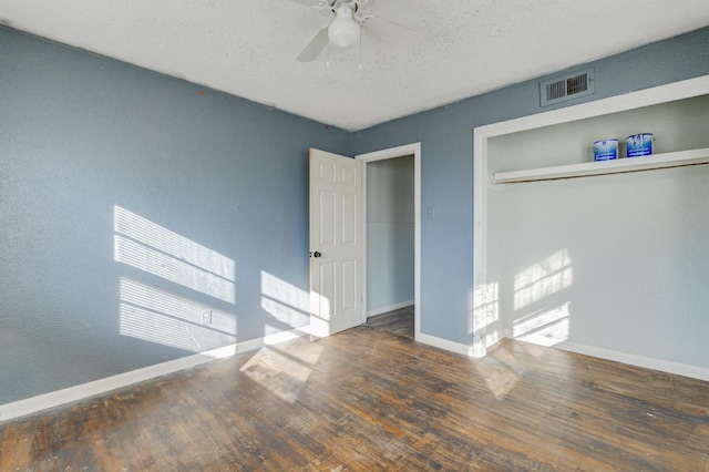 unfurnished bedroom with ceiling fan, a closet, dark hardwood / wood-style floors, and a textured ceiling