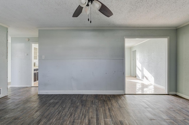 empty room featuring crown molding, ceiling fan, dark wood-type flooring, and a textured ceiling