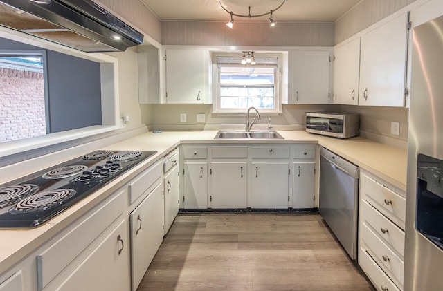 kitchen featuring sink, appliances with stainless steel finishes, light hardwood / wood-style floors, white cabinets, and exhaust hood