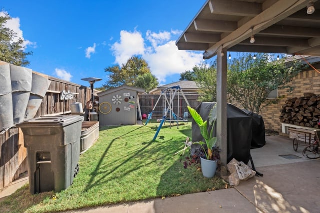 view of yard featuring a storage shed, a playground, and a patio area