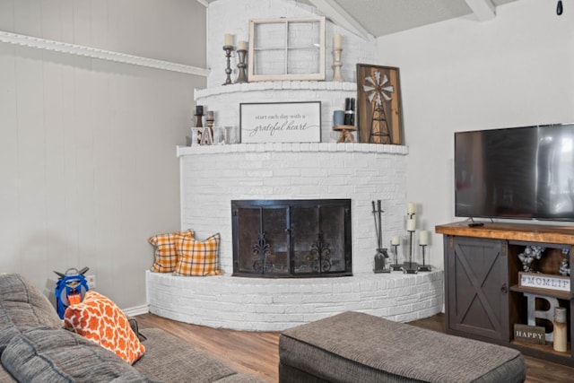 living room with vaulted ceiling, a brick fireplace, and hardwood / wood-style floors