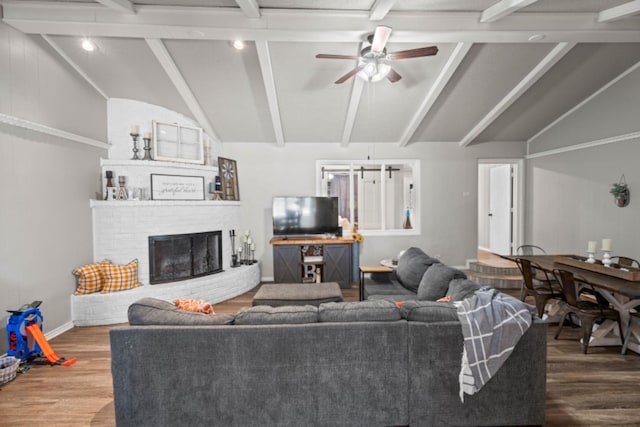 living room with lofted ceiling with beams, hardwood / wood-style floors, and a fireplace