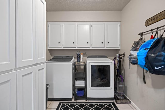 laundry area with cabinets, light tile patterned flooring, washer and dryer, and a textured ceiling